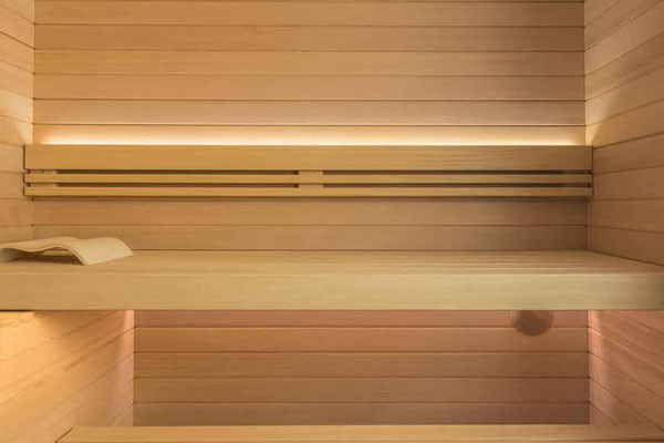 Panche in legno chiaro di una sauna finlandese con luce LED sotto lo schienale